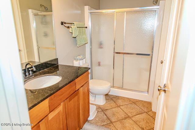 bathroom with vanity, a shower with shower door, tile patterned floors, and toilet