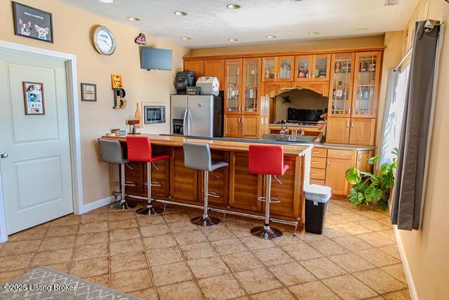 kitchen featuring stainless steel fridge, a kitchen bar, and kitchen peninsula