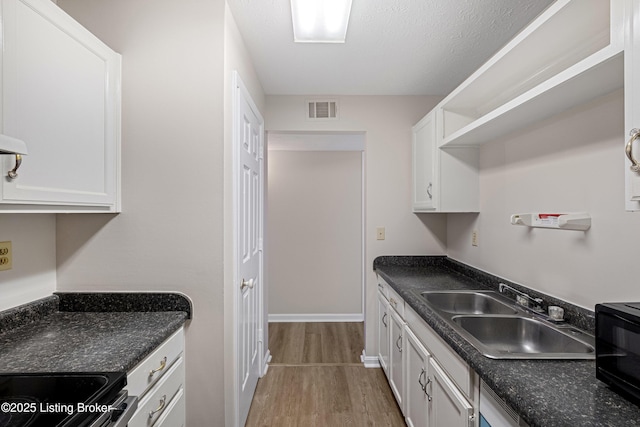 kitchen with range with electric cooktop, white cabinetry, wood-type flooring, sink, and a textured ceiling