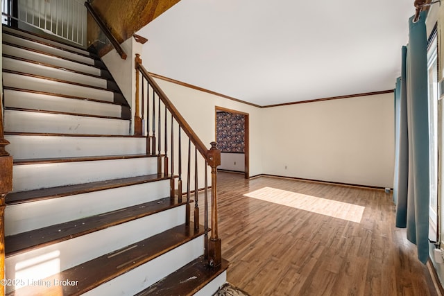 staircase with wood-type flooring and crown molding