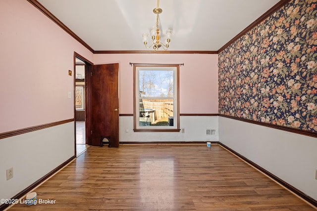 unfurnished room featuring crown molding, wood-type flooring, and a chandelier