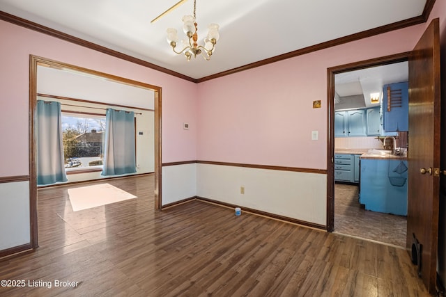 unfurnished room featuring ornamental molding, dark wood-type flooring, sink, and a chandelier