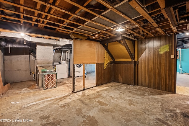 basement with washing machine and clothes dryer and wood walls