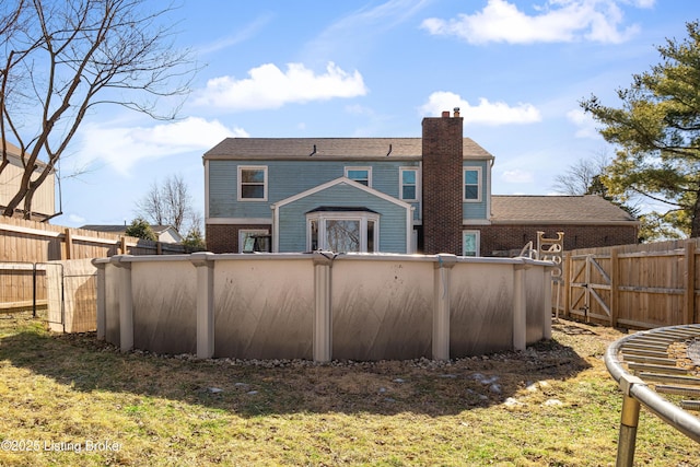 back of house featuring a fenced in pool and a lawn