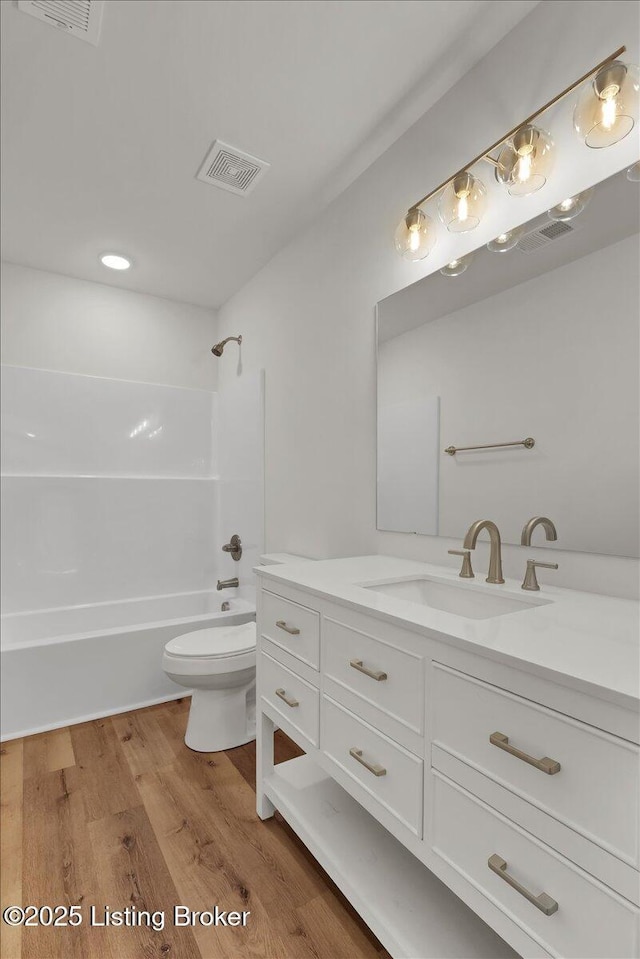 full bathroom featuring hardwood / wood-style flooring, vanity, toilet, and bathtub / shower combination