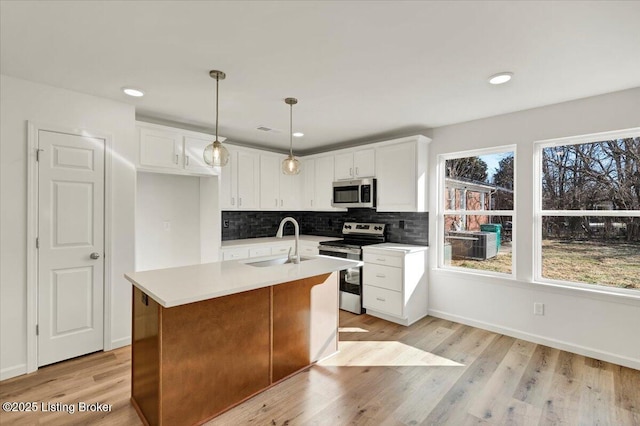 kitchen featuring sink, white cabinetry, decorative light fixtures, a center island with sink, and appliances with stainless steel finishes