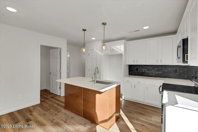 kitchen with white cabinetry, sink, stainless steel appliances, and an island with sink