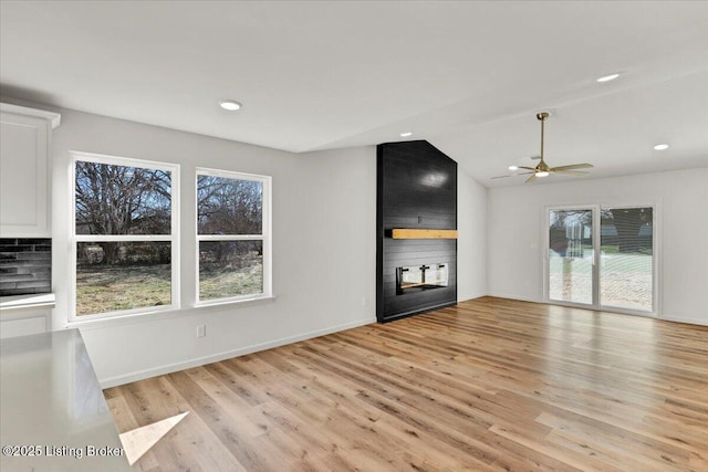 unfurnished living room featuring light hardwood / wood-style flooring, a fireplace, ceiling fan, and vaulted ceiling