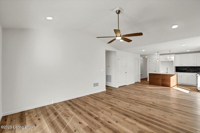 unfurnished living room with sink, vaulted ceiling, light hardwood / wood-style floors, and ceiling fan