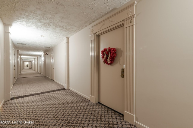 corridor with light colored carpet and a textured ceiling