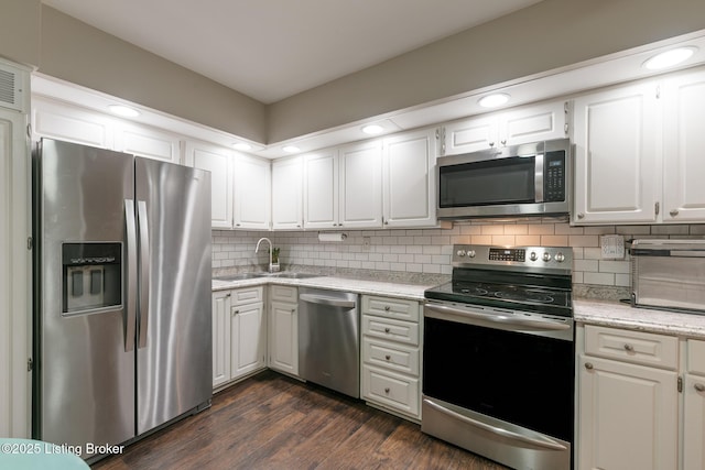 kitchen featuring sink, dark wood-type flooring, appliances with stainless steel finishes, white cabinets, and decorative backsplash