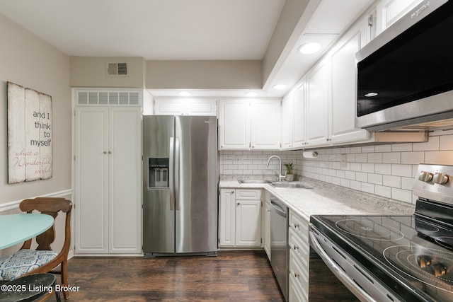 kitchen featuring sink, white cabinets, backsplash, stainless steel appliances, and dark wood-type flooring