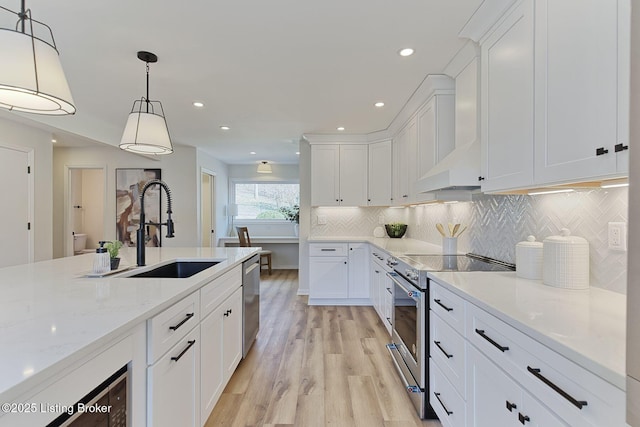 kitchen with appliances with stainless steel finishes, white cabinetry, sink, hanging light fixtures, and light stone counters