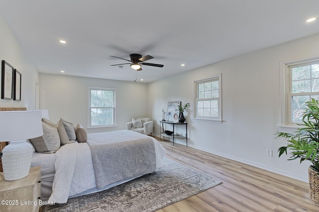 bedroom with multiple windows, light hardwood / wood-style floors, and ceiling fan