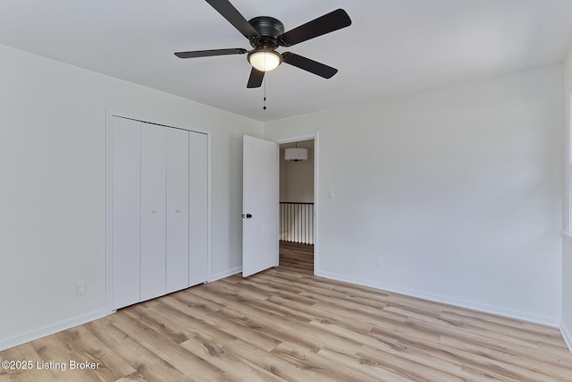 unfurnished bedroom featuring ceiling fan, a closet, and light wood-type flooring