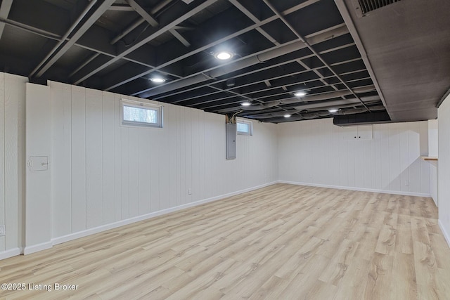 basement with light hardwood / wood-style flooring and electric panel