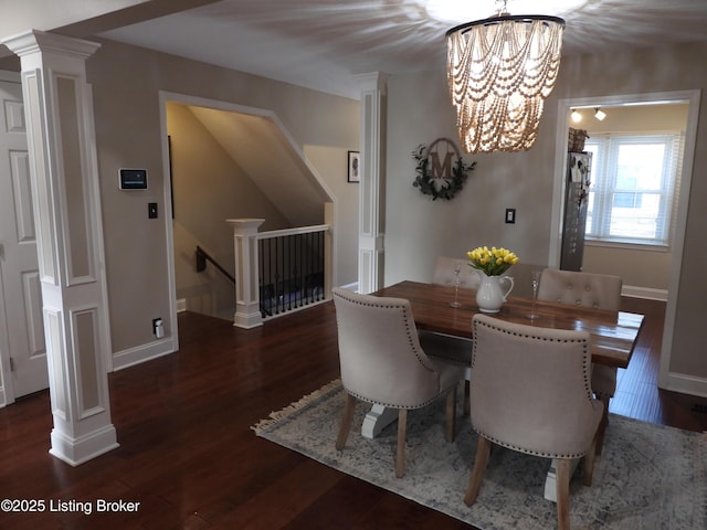 dining room with dark hardwood / wood-style flooring, a notable chandelier, and ornate columns