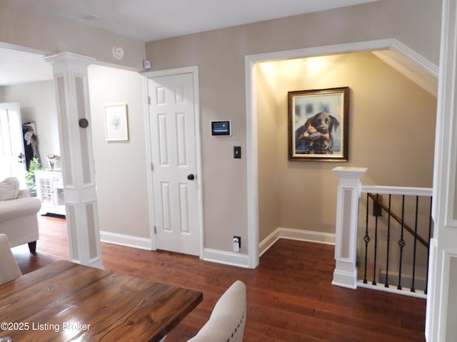 corridor featuring decorative columns and dark wood-type flooring