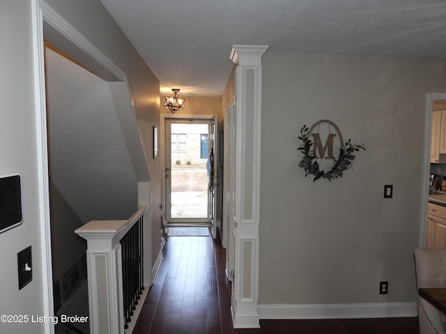 entrance foyer with dark hardwood / wood-style flooring, decorative columns, and a textured ceiling