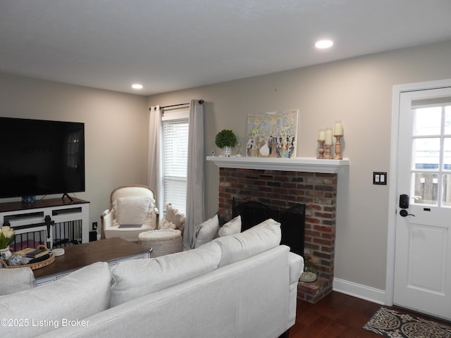 living room with dark hardwood / wood-style floors, a brick fireplace, and a wealth of natural light