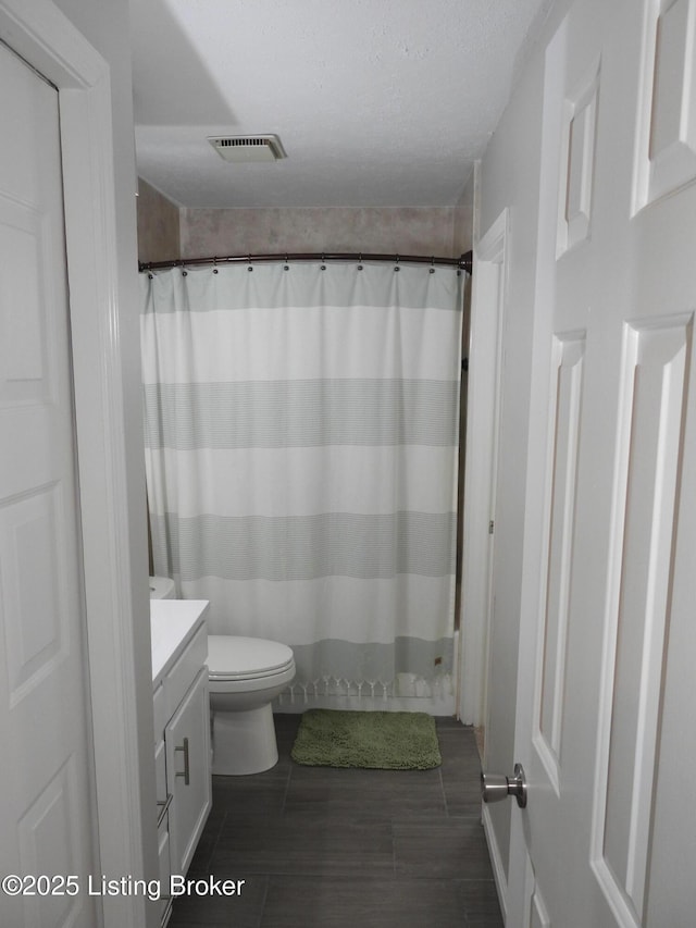 bathroom with vanity, toilet, and a textured ceiling