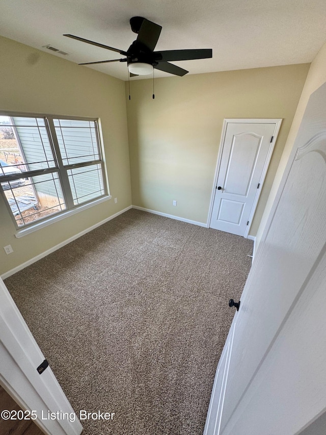 unfurnished room with ceiling fan and carpet