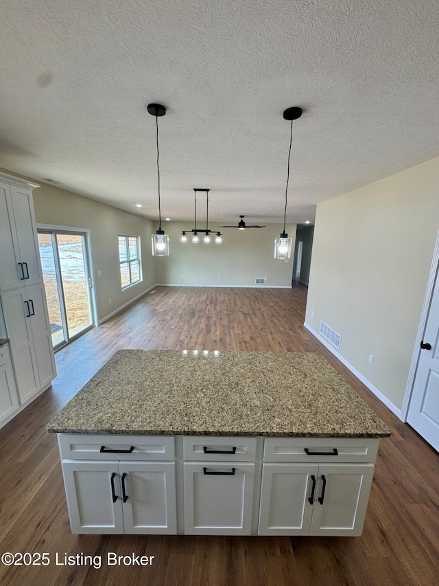 kitchen with light stone countertops, a center island, and white cabinets