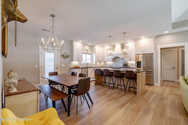 dining room with sink, light hardwood / wood-style floors, and a notable chandelier