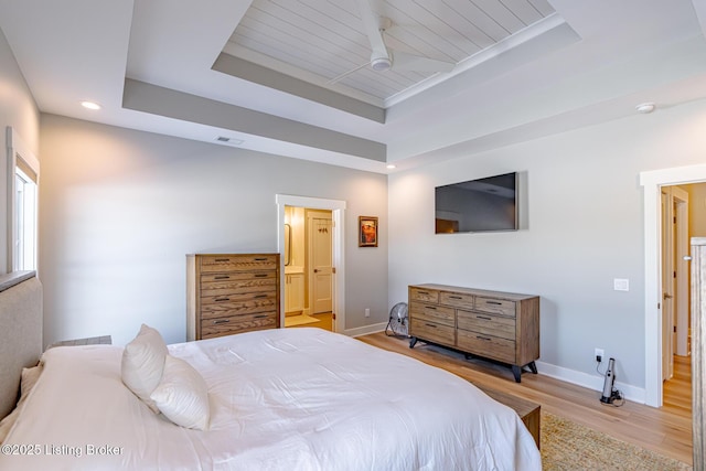 bedroom with ensuite bath, a raised ceiling, light hardwood / wood-style floors, and wooden ceiling