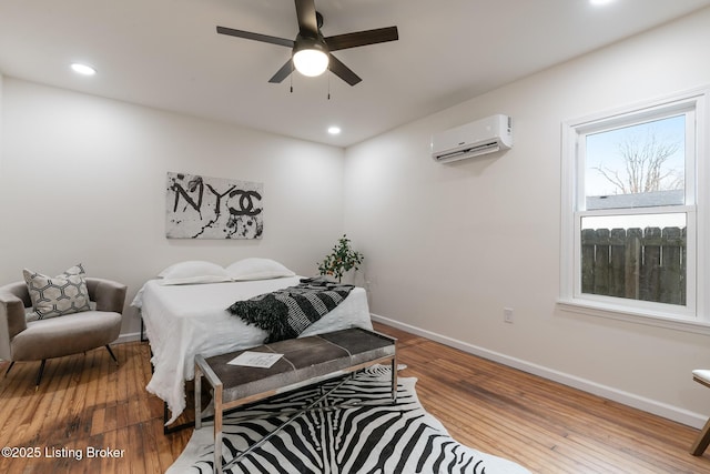 bedroom featuring wood-type flooring, a wall mounted AC, and ceiling fan