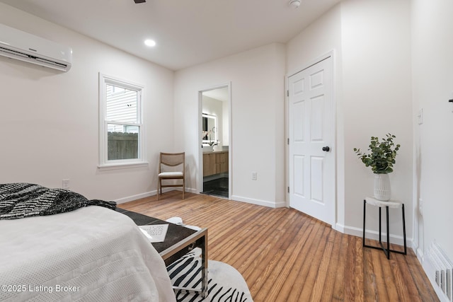 bedroom with ensuite bath, wood-type flooring, and a wall mounted AC