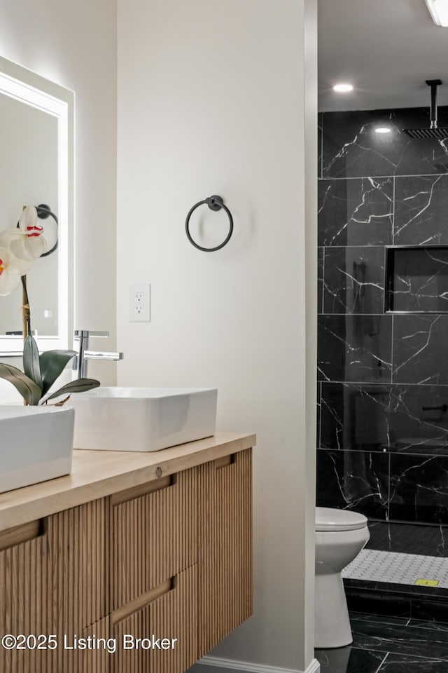 bathroom featuring tiled shower, vanity, and toilet