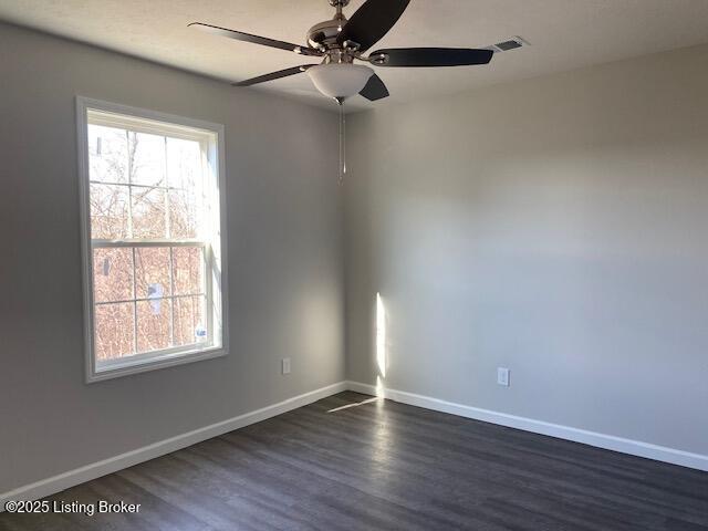 spare room featuring dark wood-type flooring and ceiling fan