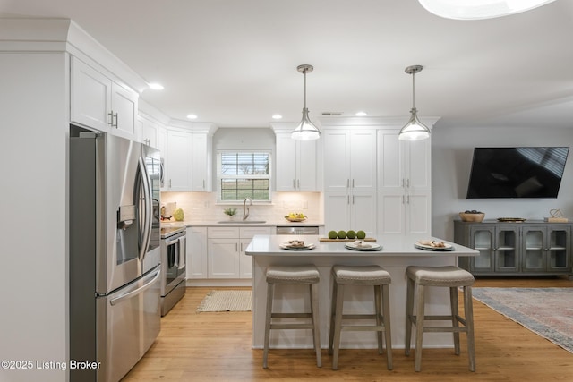 kitchen featuring hanging light fixtures, a kitchen breakfast bar, white cabinets, and appliances with stainless steel finishes