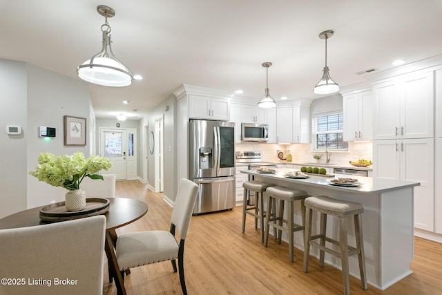 kitchen featuring white cabinetry, appliances with stainless steel finishes, a center island, and pendant lighting