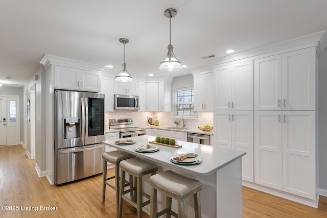 kitchen with sink, white cabinetry, hanging light fixtures, a kitchen breakfast bar, and stainless steel appliances