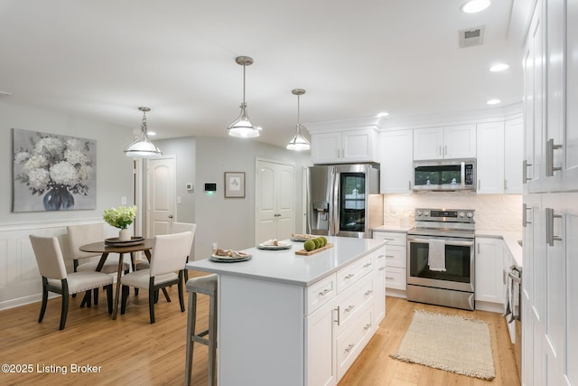 kitchen featuring white cabinetry, appliances with stainless steel finishes, a kitchen island, and pendant lighting