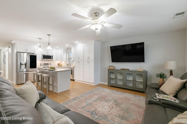 living room with ceiling fan and light hardwood / wood-style floors