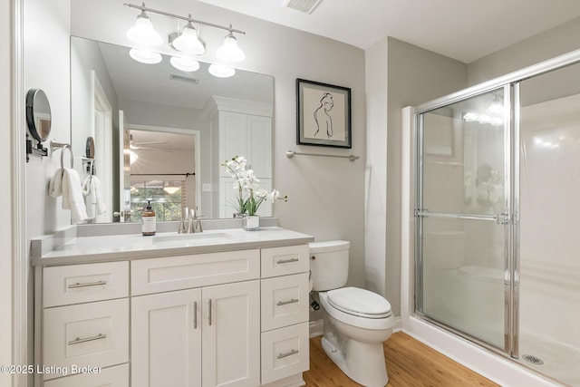 bathroom featuring a shower with door, vanity, hardwood / wood-style flooring, and toilet