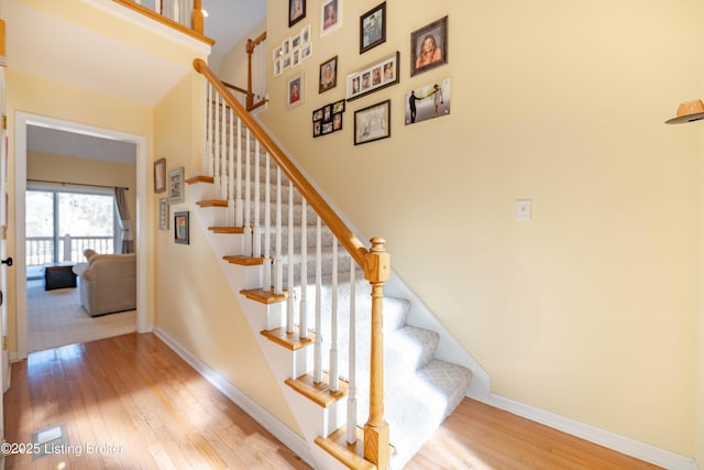 stairs featuring hardwood / wood-style flooring and a towering ceiling