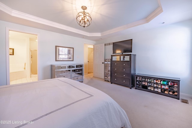 bedroom with an inviting chandelier, ensuite bathroom, a tray ceiling, ornamental molding, and light carpet