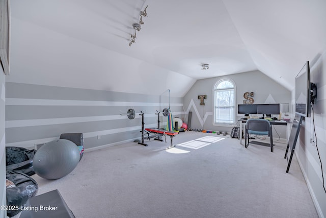 exercise room featuring light colored carpet, track lighting, and vaulted ceiling