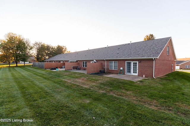 back house at dusk featuring a patio, a yard, and french doors