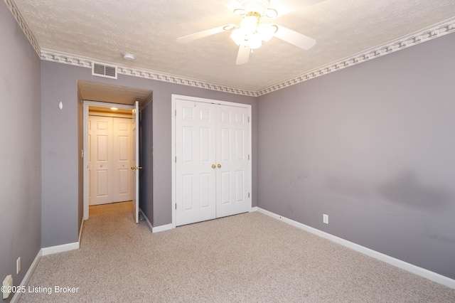 unfurnished bedroom featuring ceiling fan, a closet, carpet floors, and a textured ceiling