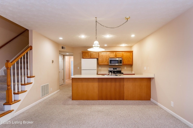 kitchen with stainless steel appliances, hanging light fixtures, light colored carpet, and kitchen peninsula