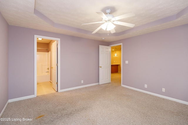 unfurnished bedroom featuring light carpet, a raised ceiling, and a textured ceiling