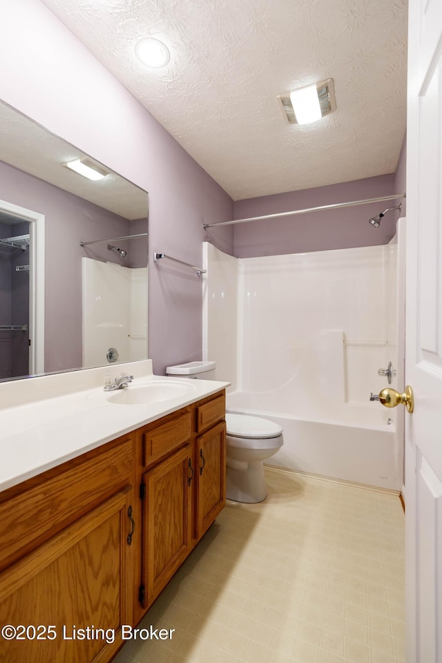 full bathroom with vanity, toilet,  shower combination, and a textured ceiling