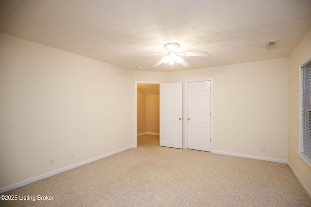 unfurnished bedroom with ceiling fan, light carpet, and a textured ceiling