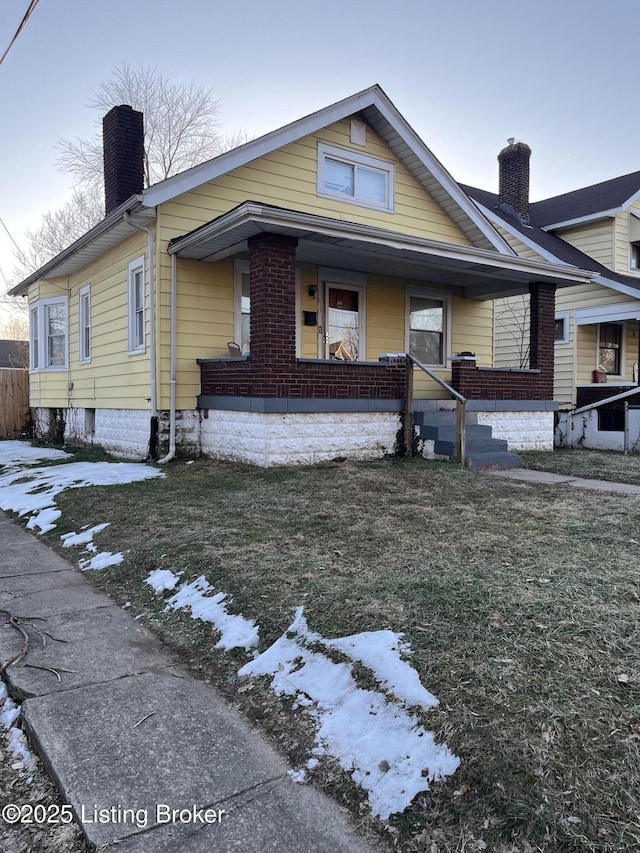 bungalow-style home with a lawn and covered porch