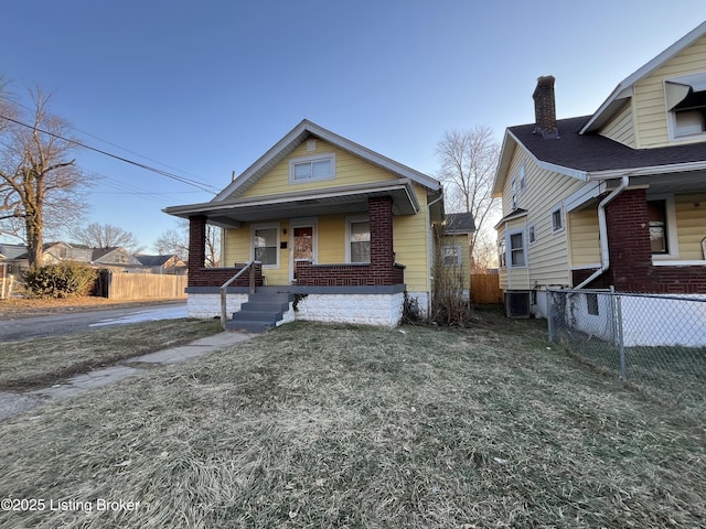 bungalow-style house with a front yard, cooling unit, and covered porch